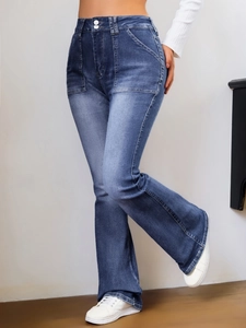 Détail du jean évasé à taille haute en bleu foncé avec double boutonnage et grandes poches plaquées