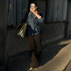 Chemise en jean bleu foncé à nouer, jupe longue marron et sac cabas doré de style moderne