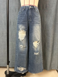 Detail van lichtblauwe wide-leg jeans met zware slijtage en vintage wassing textuur