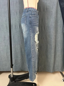 Detail van zware slijtage en grote gescheurde gaten op de donkerblauwe wide-leg spijkerbroek