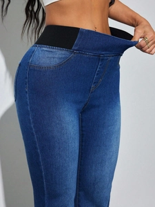 Detailed view of dark blue flare jeans featuring high-waist elastic band and orange stitching