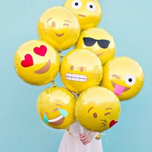 Bunch of yellow emoji foil balloons for birthday party decoration on blue background