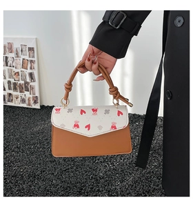 Detail showing knotted handle and pink bear print on contrast color mini square bag