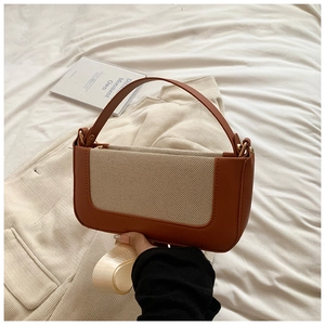 Detailed view of a brown leather and beige canvas handbag with dual strap options