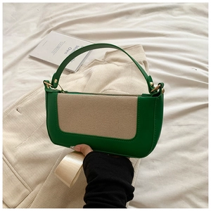 Detail view of green leather and beige canvas patchwork handbag with gold metal zippers