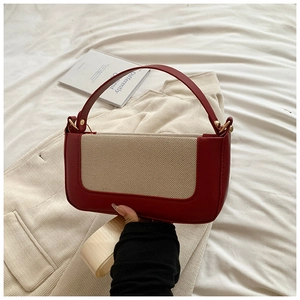 Detail view of the burgundy leather and beige canvas contrast stitching on the handbag