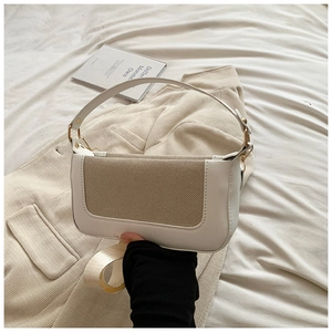 Detail of white and beige box bag featuring gold hardware and removable woven strap