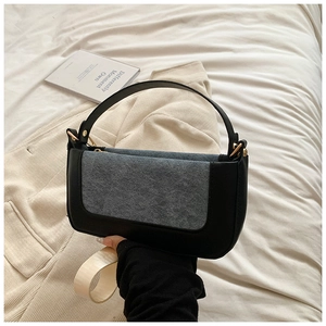 Detail of grey suede and black leather patchwork bag with gold hardware and top handle