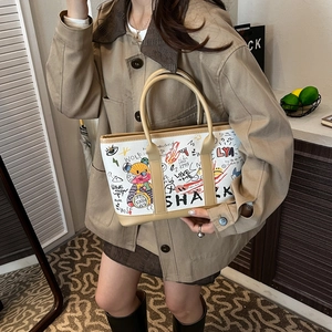 Artistic graffiti print tote bag with bear motif and khaki handles shown on model