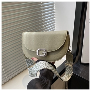 Detail of green lychee leather saddle bag with silver G buckle and geometric woven strap