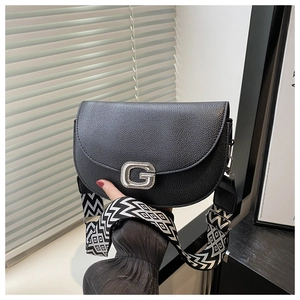 Detail of black lychee grain saddle bag featuring a rhinestone G-buckle and geometric strap