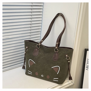 Detail of olive green tote bag featuring a cute cartoon cat face and dark brown handles