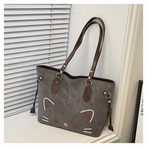 Close-up of minimalist cat face print on a grey leather tote bag with brown handles