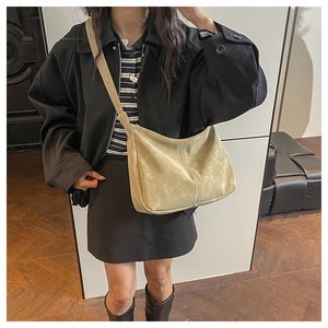 Détail du sac bandoulière beige demi-lune porté avec un haut à rayures et une veste
