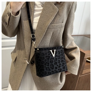 Close-up of leopard pattern crossbody bag with gold V-logo and black adjustable strap