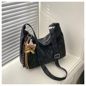 Detailed texture of black crescent bag featuring silver hardware and plush bear charm