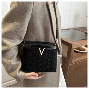 Close-up of leopard print small square bag with gold V-shape buckle on model's outfit