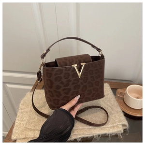 Détail du sac à main léopard avec boucle en V dorée et poignée en cuir robuste