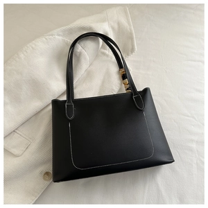 Detail of a black tote bag with white contrast stitching and a decorative silk scarf