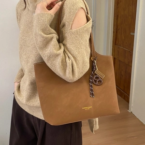 Gros plan du sac cabas marron avec texture cuir, logo mode et pendentif bretzel