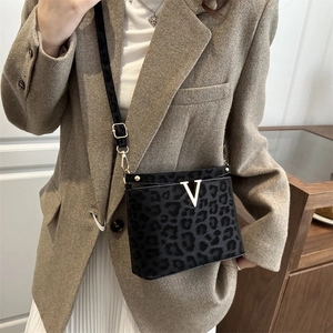 Sac bandoulière chic à motif léopard noir avec logo V doré porté par un mannequin