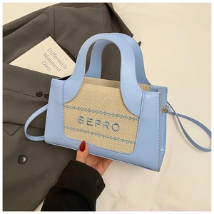 Detail of light blue leather and beige canvas stitching on a square crossbody bag
