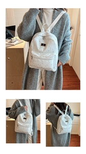 Close-up of white star print backpack showing metal logo plaque and canvas texture