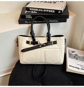 Detail of minimalist cream crossbody bag with black handle on a modern stool