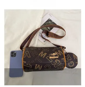Brown Boston bag with logo pattern, mini purse and shoulder strap beside a phone