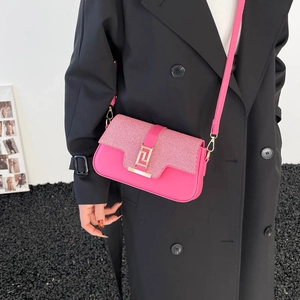 Borsa a sella rosa acceso con catena e fibbia dorata su un cappotto nero lungo
