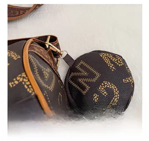 Close-up of golden metal hooks on a vintage brown monogram cylinder bag with textures