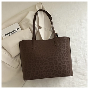 Deep brown leopard print tote bag with decorative scarf on white blazer background