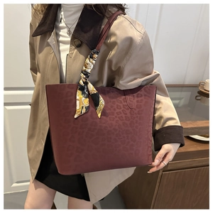 Detail of burgundy leopard embossed suede tote bag with decorative patterned silk scarf