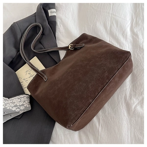 Detail showing vintage brown tote bag with white contrast stitching and grainy leather texture
