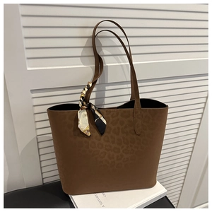 Detail of leopard print tote bag with decorative silk scarf on white wooden background