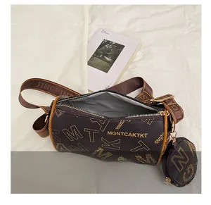 Detail view of brown cylinder Boston bag with yellow lettering and wide shoulder strap
