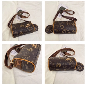 Detailed view of tan Boston bag with monogram print, wide strap, and mini pouch charm