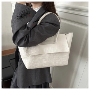 White crocodile pattern tote bag with flap closure shown on a model in gray blazer