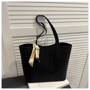Detail of black leopard print tote bag featuring a decorative beige patterned silk scarf