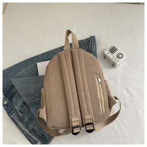 Detailed back view of a corduroy backpack showing adjustable straps and back zipper pocket