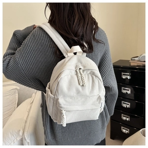Detail of cream corduroy backpack with vertical stripes and knotted zipper puller