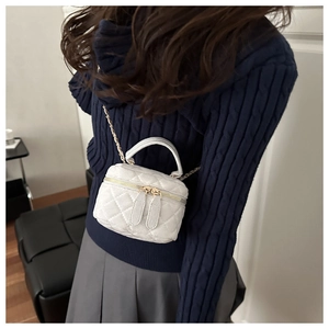 Detalle de cerca del mini bolso caja acolchado blanco con cadena dorada y cremallera