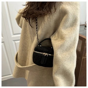 Vista lateral del mini bolso acolchado negro con cadena dorada sobre abrigo beige
