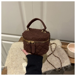 Detalle de un bolso bandolera acolchado marrón oscuro con cadena dorada y terciopelo