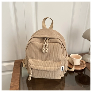 Detailed close-up of corduroy texture and fashion woven label on khaki backpack