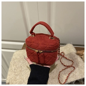 Detalle de bolso vanity de tweed rojo acolchado con cadena dorada y asa superior