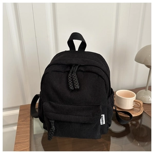 Detail view of black corduroy mini backpack with woven zipper pull and fashion side label