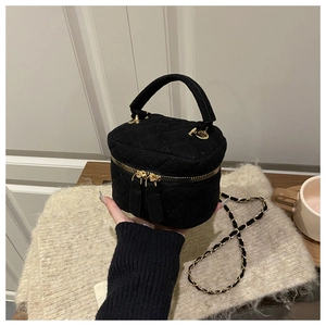 Detalle de bolso bandolera acolchado negro con cadena dorada y acabado de tela texturizada