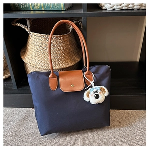 Close-up of navy nylon tote bag with brown handles and a cute plush dog charm