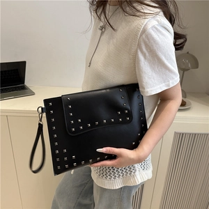 Fashionable black studded shoulder bag for women in a minimalist office setting
